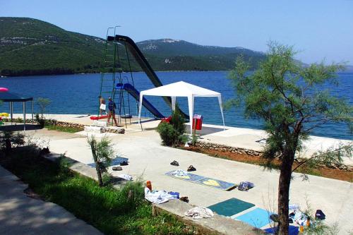 un parque infantil con un tobogán junto al agua en Rooms by the sea Luka, Dugi otok - 8132, en Žman