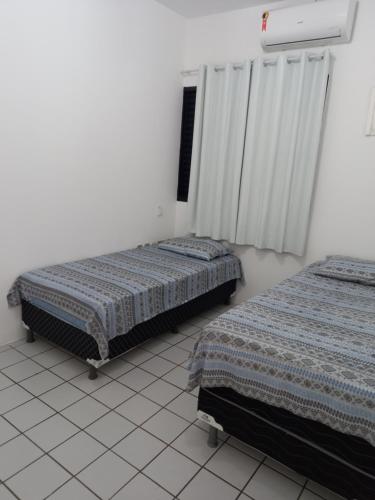 two beds in a room with white walls at Apartamento, Zona Leste, ótima localização. in Teresina