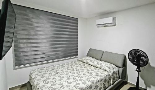 a bedroom with a bed and a window with a fan at Espectacular Penthouse dúplex bien equipado in Barranquilla