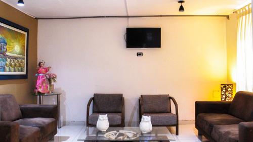 a living room with two chairs and a tv on a wall at Hotel Chimu in Trujillo
