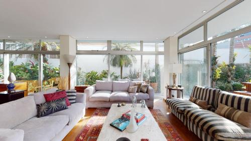 uma sala de estar com sofás e muitas janelas em Becas House em São Paulo