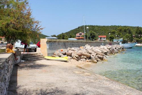 a woman sitting next to the water with a yellow kayak at Apartment Zman 887c in Žman