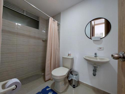 y baño con aseo, lavabo y espejo. en Apartamento Aqualina Orange Piso Octavo Vista a Piscina, en Girardot