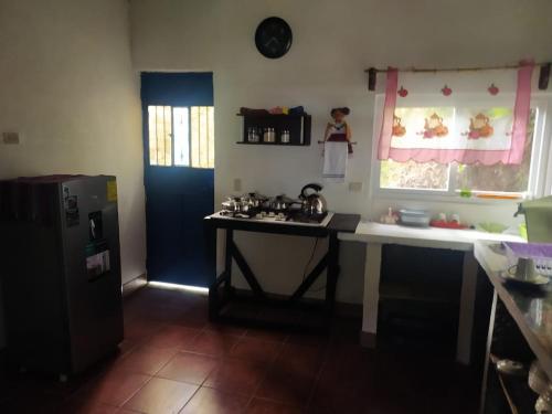 a kitchen with a table and a sink and a refrigerator at Hostal El Calvario del Bosque, Aldea Las Cruces, Cobán 
