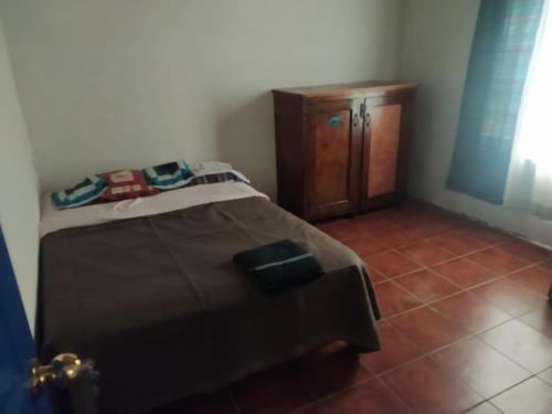 a bedroom with a bed and a wooden cabinet at Hostal El Calvario del Bosque, Aldea Las Cruces, Cobán 