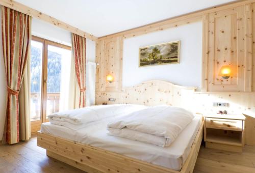 a bedroom with a large white bed in a room at Family and Wellness Residence Ciasa Antersies in San Cassiano