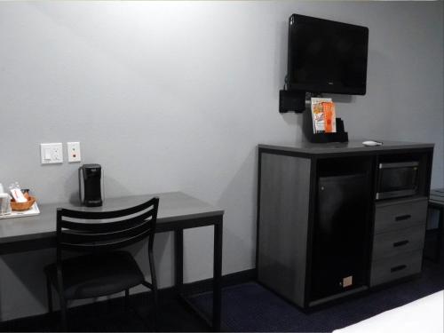 Habitación con escritorio, TV y silla. en Americas Best Value Inn and Suites Bush International Airport, en Humble