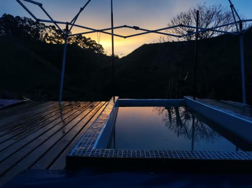 una piscina con puesta de sol en el fondo en Glamping Paraiso, en San Roque
