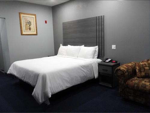 a hotel room with a bed and a chair at Americas Best Value Inn and Suites Bush International Airport in Humble