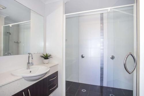 ein weißes Bad mit einem Waschbecken und einer Dusche in der Unterkunft Mollymook Luxury Beachfront Apartment 10 in Mollymook