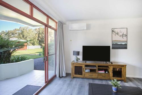 a living room with a flat screen tv on a wooden cabinet at Fathoms 3 Ocean Breeze in Mollymook
