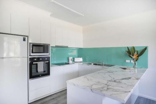 a kitchen with white cabinets and a marble counter top at Fathoms 3 Ocean Breeze in Mollymook