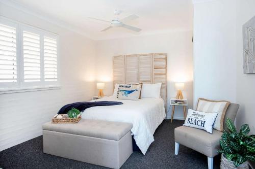 ein weißes Schlafzimmer mit einem Bett und einem Stuhl in der Unterkunft Mariners 6 in Mollymook