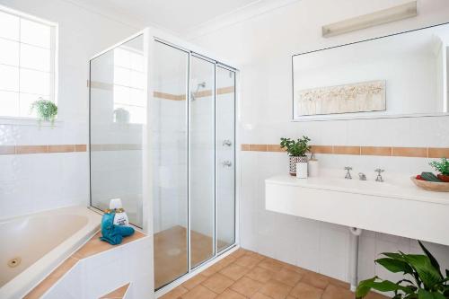 a bathroom with a shower and a tub and a sink at Mariners 6 in Mollymook