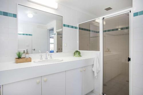 La salle de bains blanche est pourvue d'un lavabo et d'une douche. dans l'établissement Fathoms 3 Ocean Breeze, à Mollymook