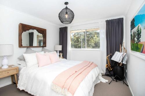een slaapkamer met een wit bed en een raam bij Relax at The Sands in Mollymook