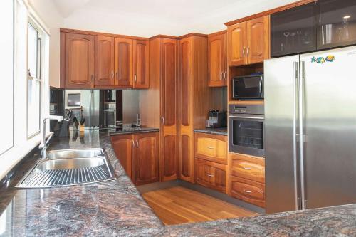 a kitchen with wooden cabinets and a stainless steel refrigerator at Aegean on the Beach in Narrawallee