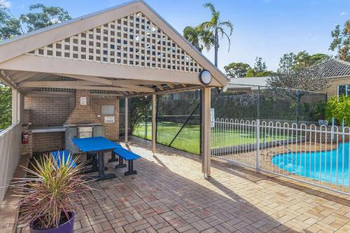 a pavilion with a picnic table and a swimming pool at Relax at The Sands in Mollymook