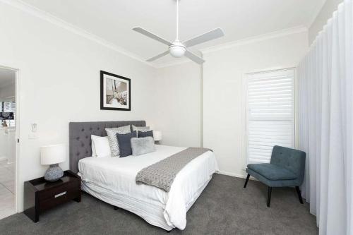 a white bedroom with a bed and a blue chair at Beachfront Eight in Mollymook