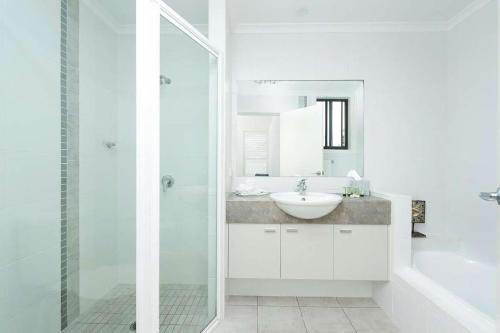 ein weißes Bad mit einem Waschbecken und einer Dusche in der Unterkunft Beachfront Eight in Mollymook