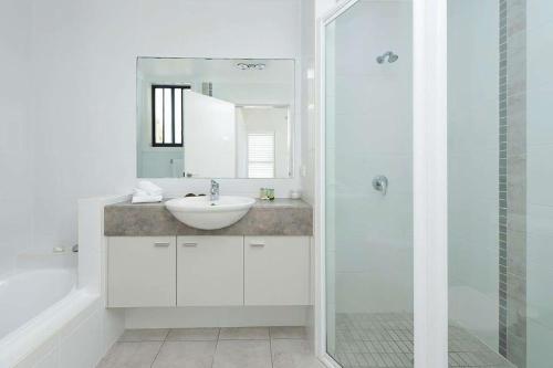 a white bathroom with a sink and a shower at Beachfront Eight in Mollymook