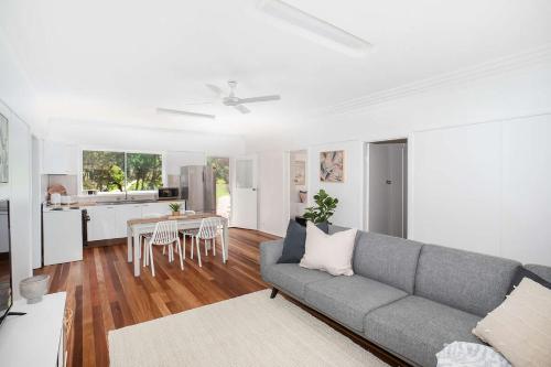 a living room with a couch and a kitchen at Barefoot Bungalow in Mollymook