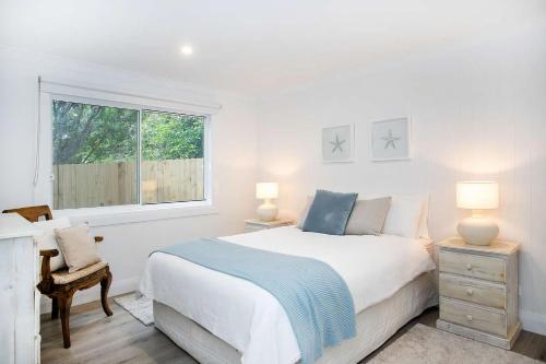 a white bedroom with a large bed and a window at SurfBreak on Seaside in Burrill Lake