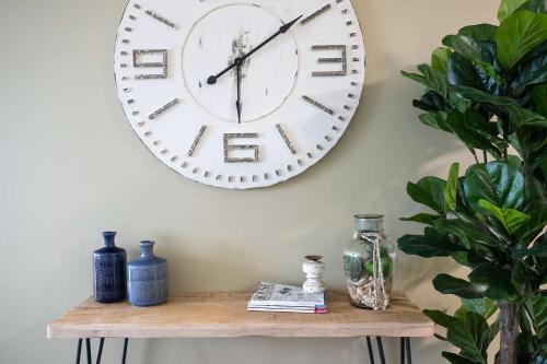 a large clock hanging on a wall above a shelf at Beachfront Six in Mollymook