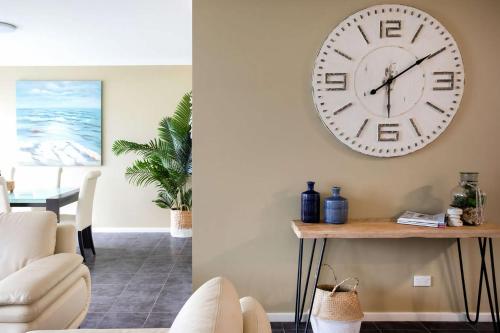 a living room with a large clock on the wall at Beachfront Six in Mollymook