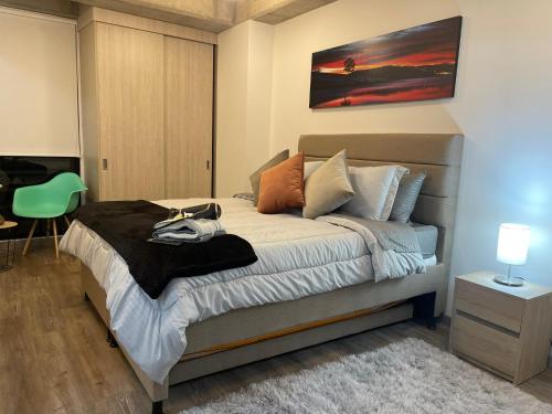 una camera con letto e sedia verde di St. Louis Suites - Movistar Arena a Bogotá