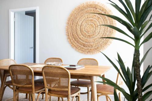 a dining room table with rattan chairs and a plant at Marina View in Ulladulla