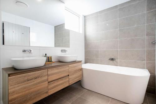 a bathroom with a white sink and a tub and a toilet at Marina View in Ulladulla