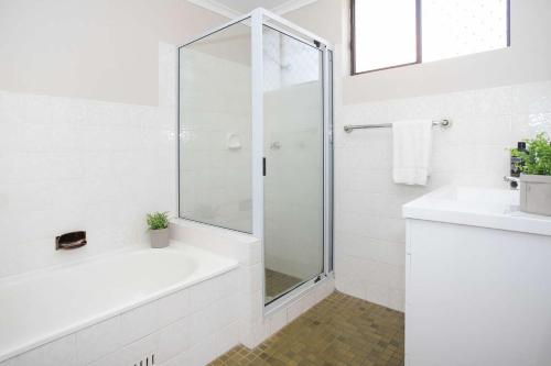 Un baño blanco con ducha y lavabo. en Surfmist One on Mollymook, en Mollymook