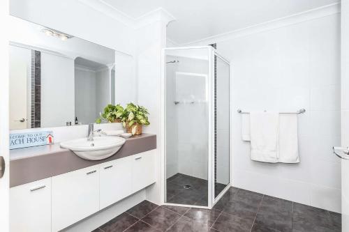 a white bathroom with a sink and a shower at Beachfront Four in Mollymook