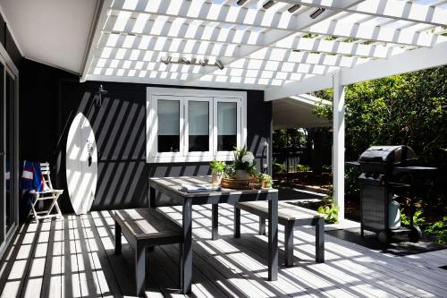 a patio with a table and chairs under a white pergola at Villa Marie in Narrawallee