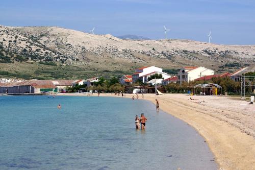 a group of people standing in the water on a beach at Apartments by the sea Pag - 11778 in Pag