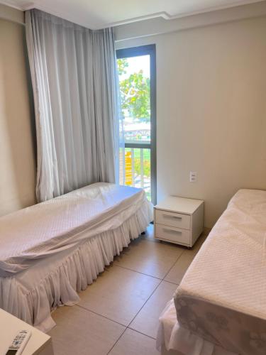 a bedroom with two beds and a window at Beach Class Muro Alto in Porto De Galinhas