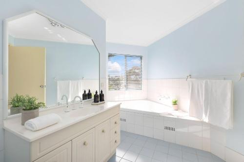 a white bathroom with a large mirror and a sink at Breakers 5 in Mollymook