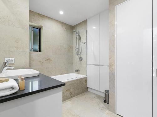 een badkamer met een bad, een wastafel en een douche bij Unit 3 Taralla 18 Edgar Bennett Avenue Noosa Heads in Noosa Heads