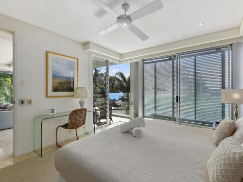 a bedroom with a bed and a desk and windows at Unit 2 Wai Cocos 215 Gympie Terrace Noosaville in Noosaville