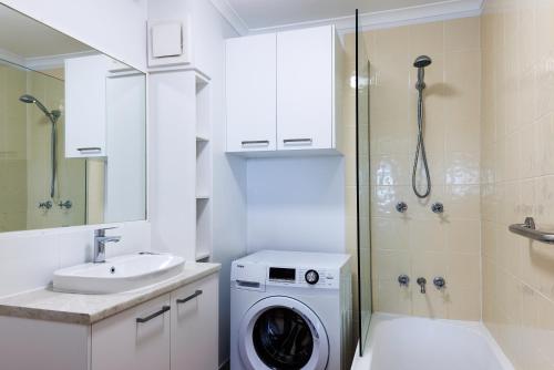 a bathroom with a washing machine and a sink at River Sands Apartments in Maroochydore