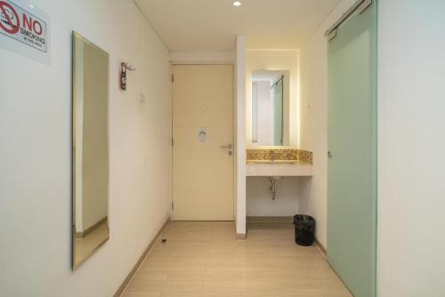 a hallway with a mirror and a sink in a room at Sans Hotel Kupang Indah Surabaya by RedDoorz in Kupang