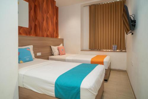 una camera d'albergo con due letti e una finestra di Sans Hotel Kupang Indah Surabaya by RedDoorz a Kupang