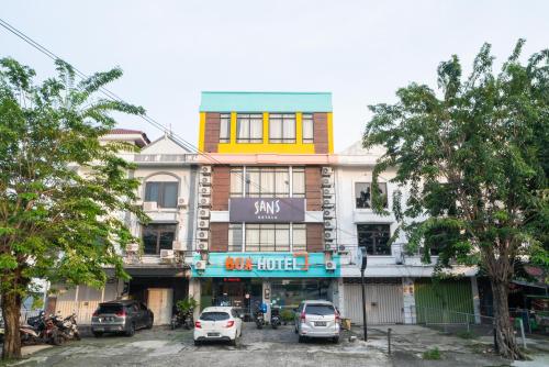 Un edificio con coches aparcados delante. en Sans Hotel Kupang Indah Surabaya by RedDoorz, en Kupang