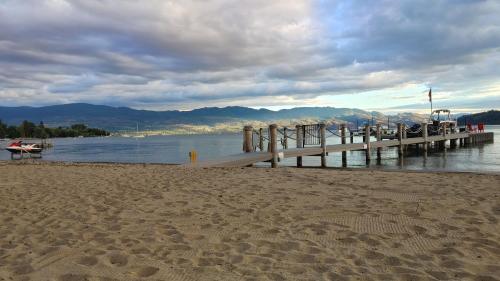 a dock on a beach next to a body of water at Beds By the Bridge in Kelowna