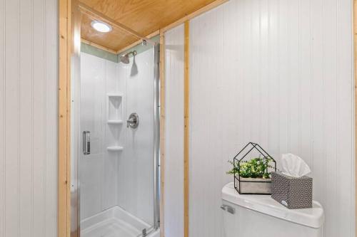 a bathroom with a shower and a toilet with a plant on it at Chasing Views Tiny House in Dandridge