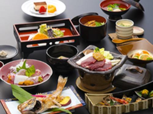 a table topped with different types of food at 湯迫温泉旅館 in Ōda