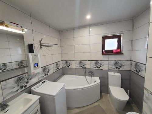 a bathroom with a tub and a toilet and a sink at Eden nad Lubie Linowno in Linowo