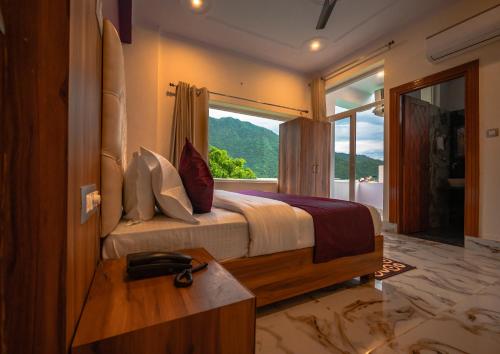 a bedroom with a bed with a large window at Hotel Rishikesh Grand by Kool-Stays in Rishīkesh