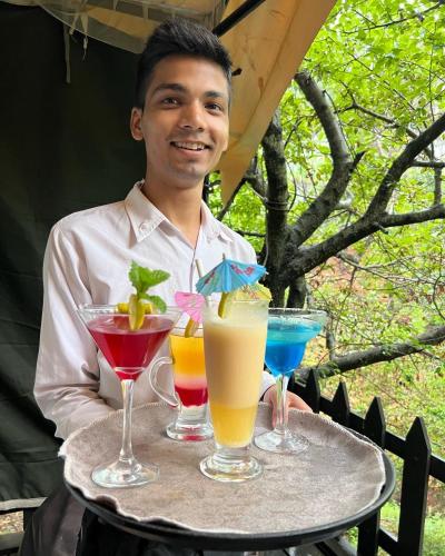 a man holding a tray with four drinks on it at Samskara & Samsara in Lansdowne